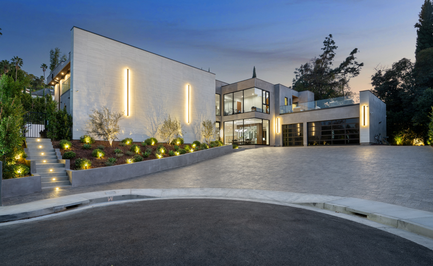 Elegant modern home featuring clean architectural lines, illuminated exterior lighting, and a spacious driveway captured at dusk for a sleek look.